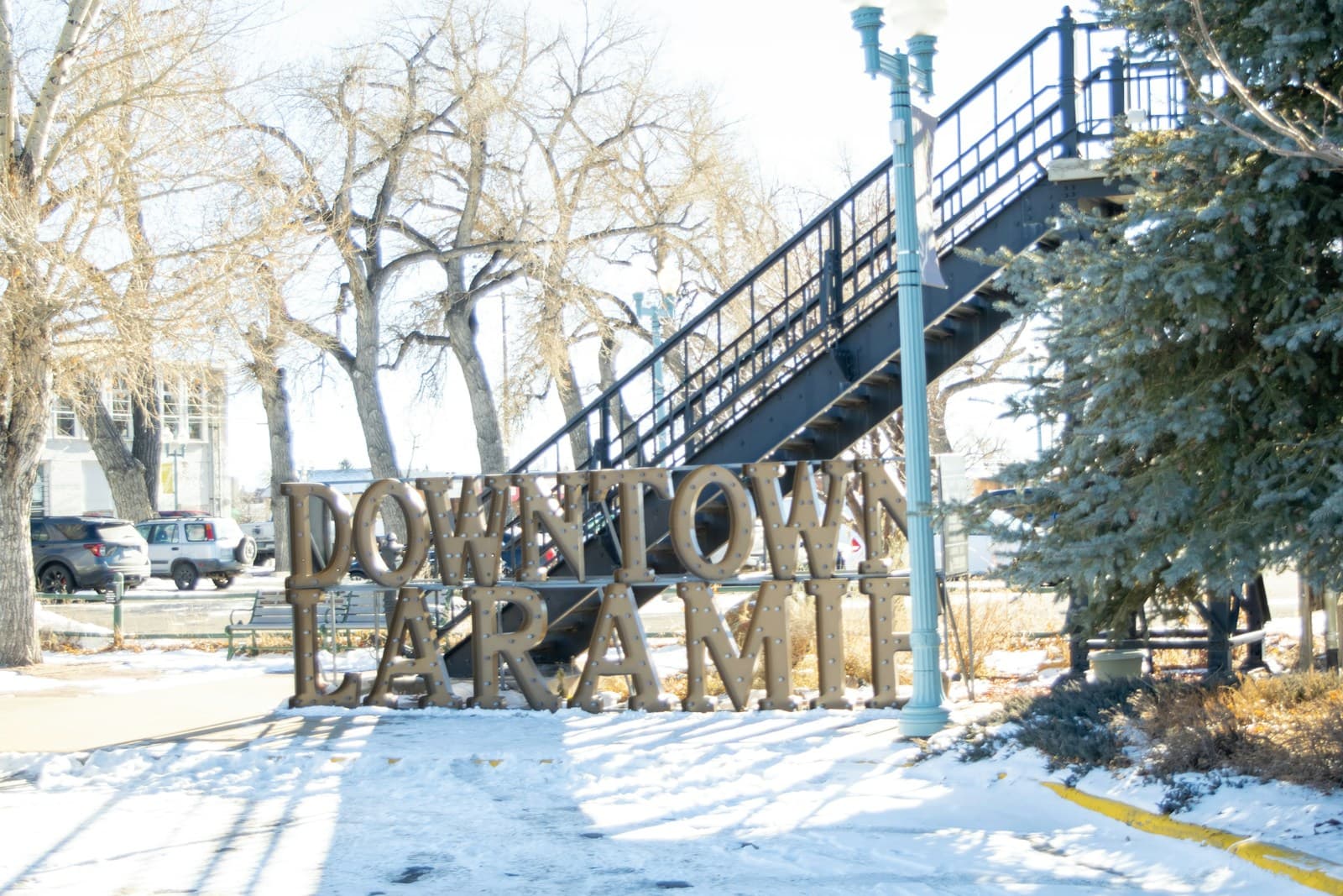 Downtown Texarkana wooden sign in snow with blue staircase structure behind it