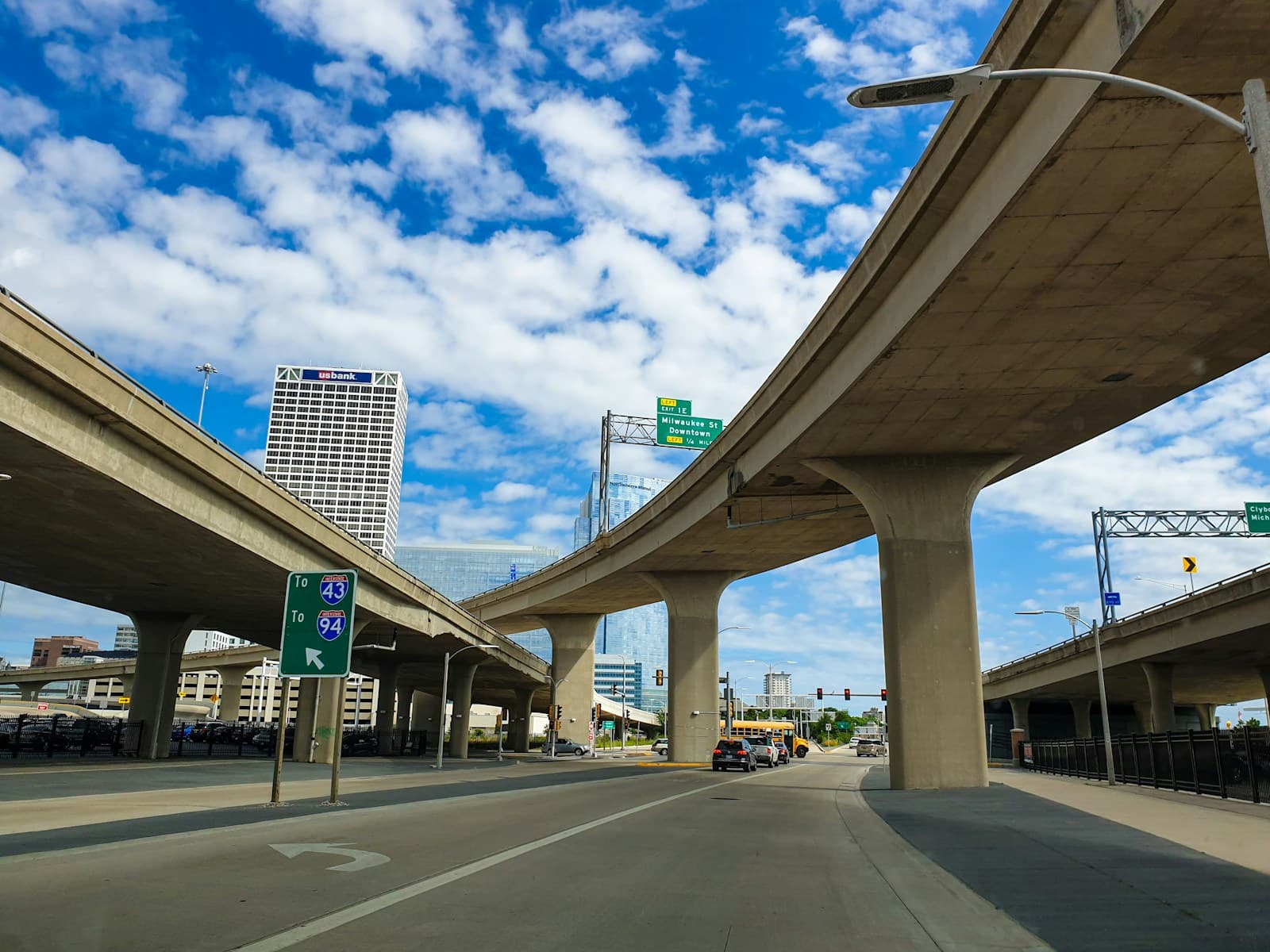 Highway interchange with concrete overpasses and elevated roads under blue cloudy sky with city buildings