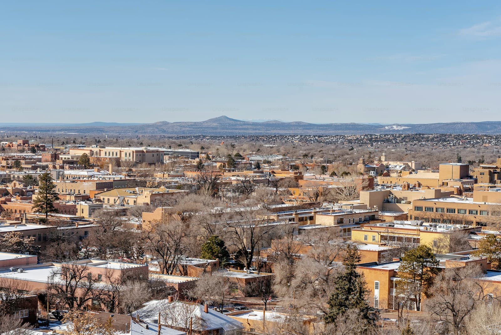 Aerial view of southwestern city in winter with snow, desert mountains, and mixed architectural styles