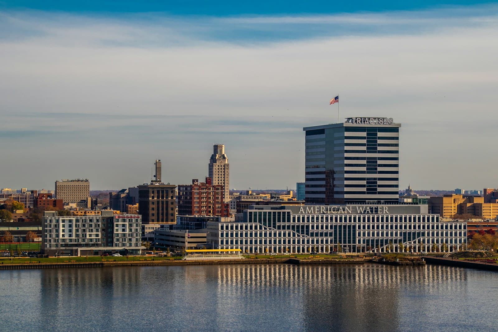 City skyline with modern buildings reflected in waterfront, featuring mix of glass towers and historic architecture